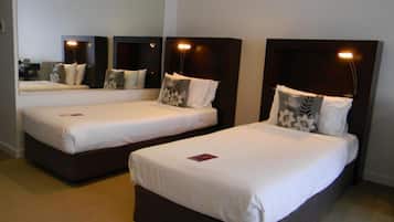 Two single beds with headboards and nightstands, a large mirror above, and a neutral carpeted floor.