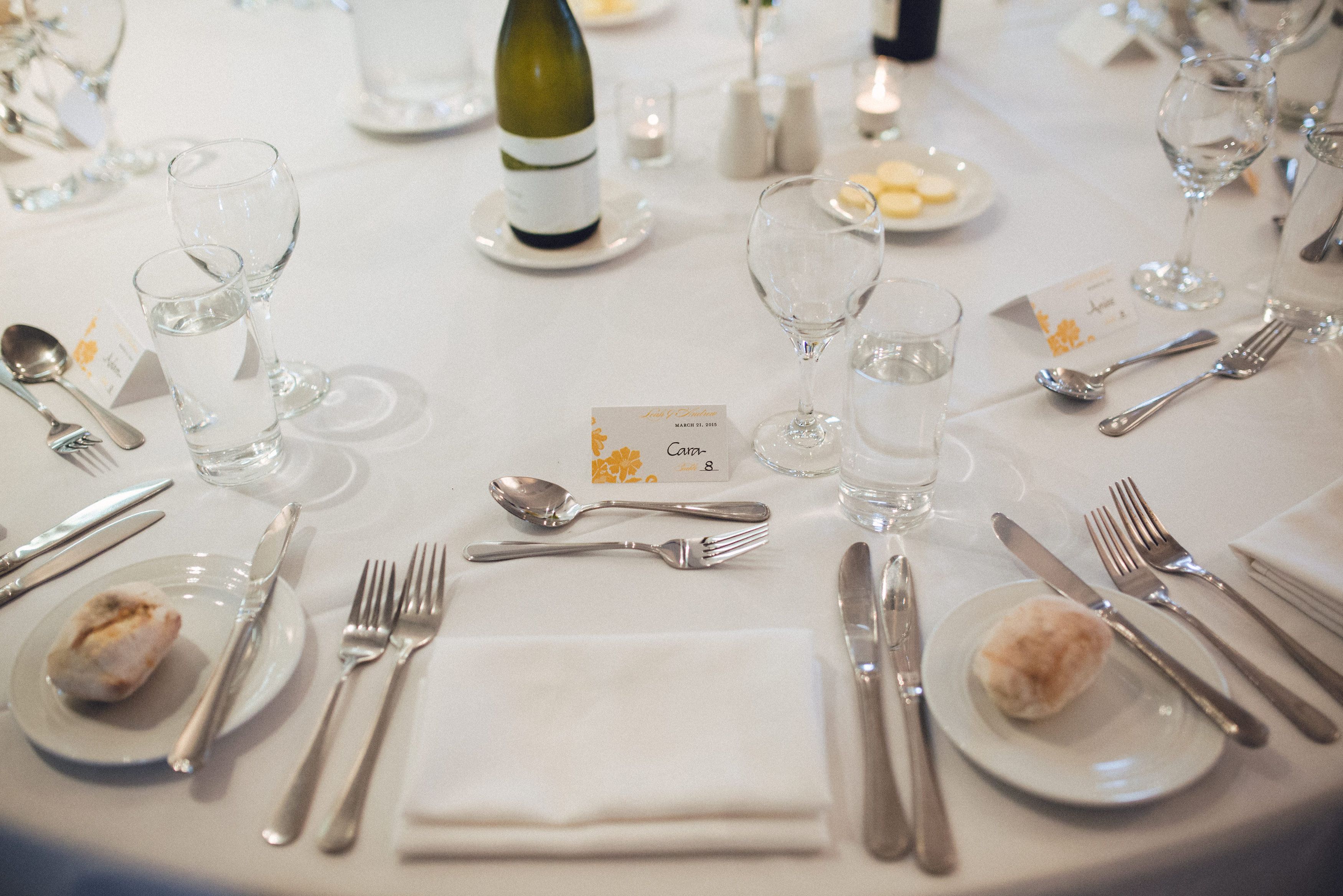 Una mesa de comedor formal dispuesta con varios vasos de vino, tenedores, cuchillos y cucharas, además de platos y una botella de vino.
