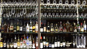 Un bar con estantes llenos de botellas de licores y una colección de copas de vino.