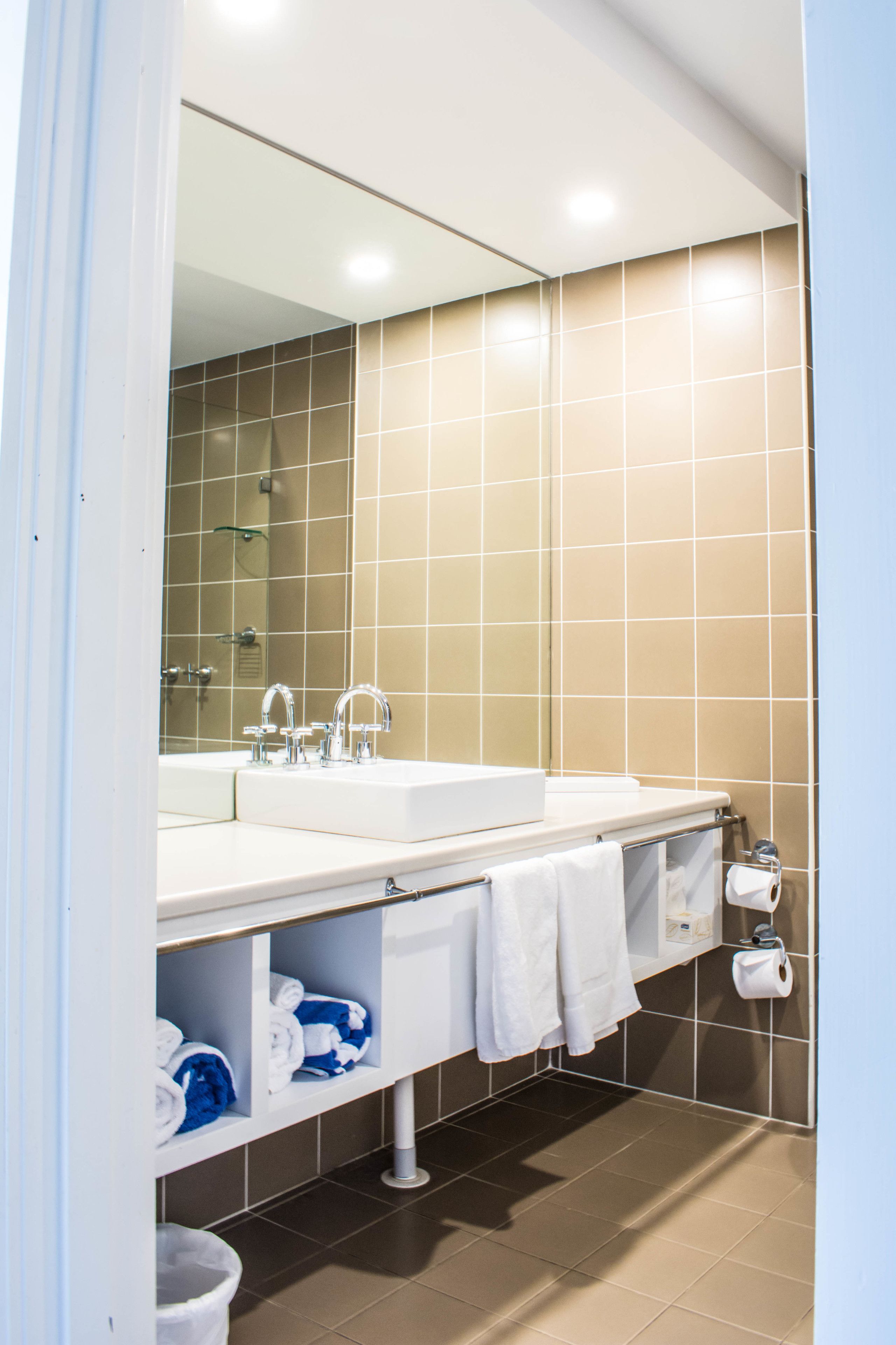 A modern bathroom with a double sink, a large mirror, and a towel rack.