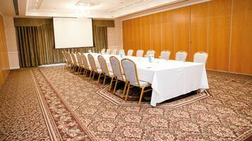 Une salle de conférence avec une longue table, des chaises, un écran de projection et une moquette à motifs.