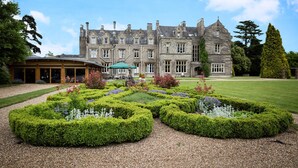A historic building with a formal garden in front, featuring neatly trimmed hedges and a central water feature. - Shendish Manor Hotel & Golf Course (Hemel Hempstead)