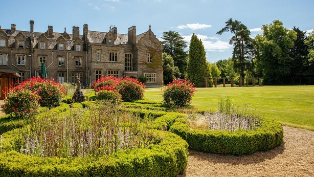 A historic stone building with a formal garden featuring neatly trimmed hedges and flowering plants. - Shendish Manor Hotel & Golf Course (Hemel Hempstead)