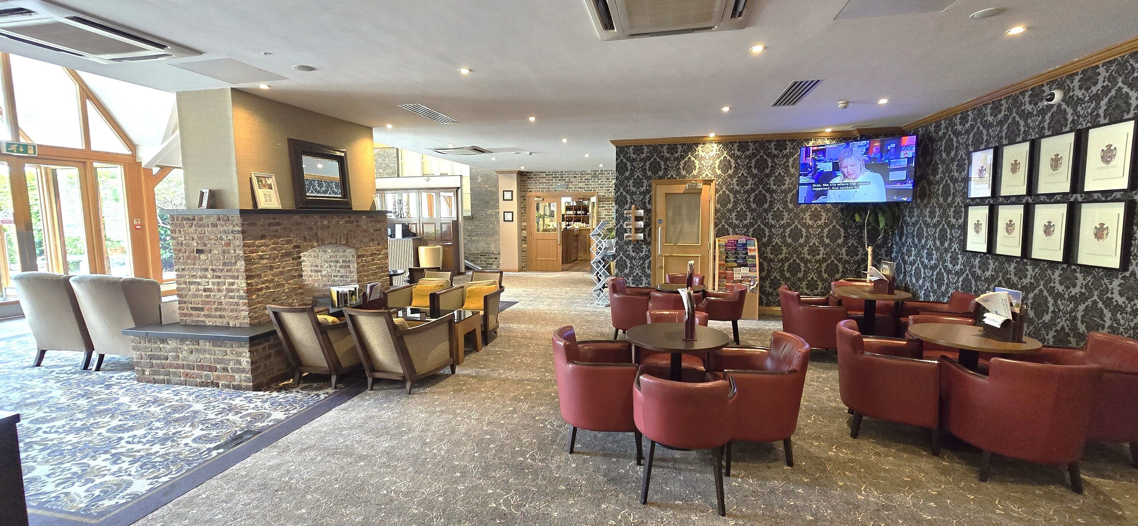 A hotel lobby with a stone fireplace, multiple seating areas, a television, and framed awards on the wall.
