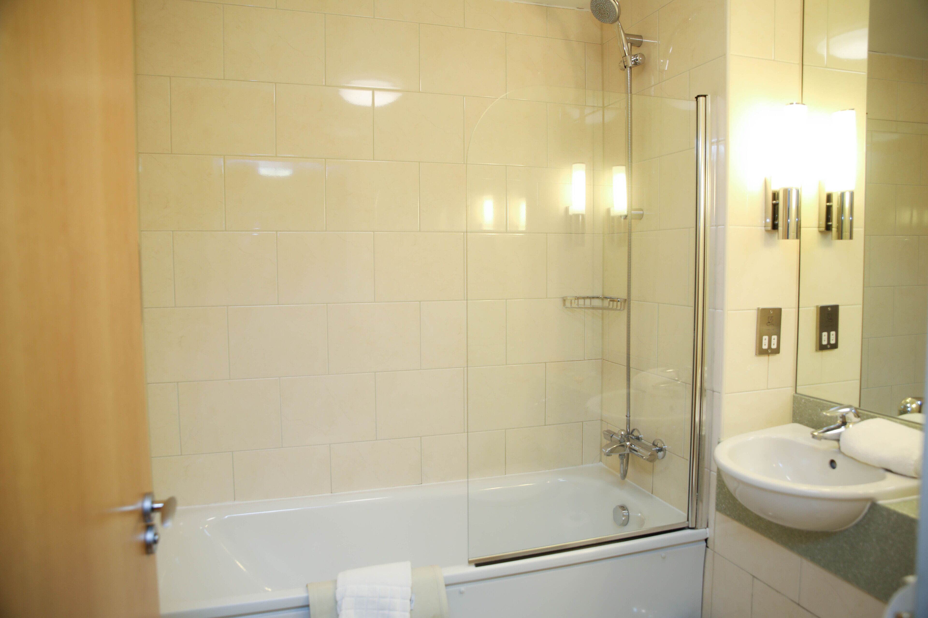 A bathroom with a bathtub, a glass-enclosed shower, and a sink.