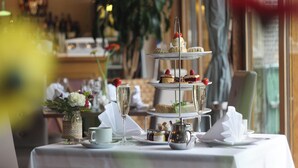 A three-tiered dessert stand with various pastries and a glass of champagne on a table. - Shendish Manor Hotel & Golf Course (Hemel Hempstead)