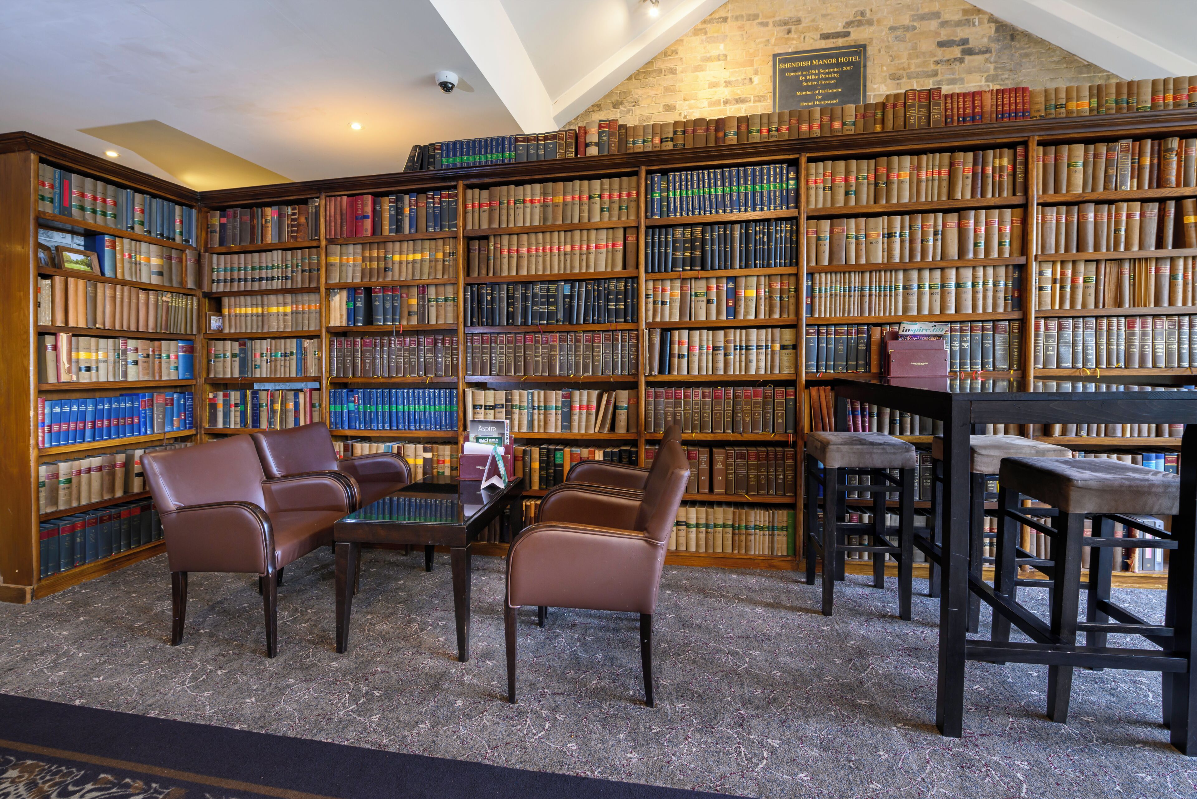 A library with bookshelves, leather chairs, and a table.