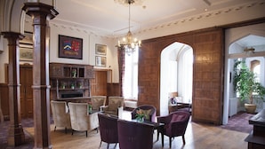 A spacious room with a wooden floor, a dining table with chairs, a chandelier, and a large window with a view. - Shendish Manor Hotel & Golf Course (Hemel Hempstead)