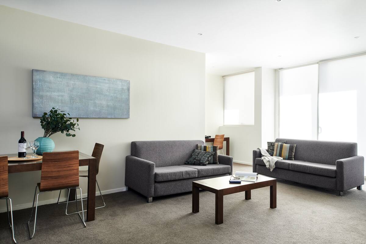 Una sala de estar moderna con dos sofás, una mesa de centro y un comedor con sillas y una mesa.