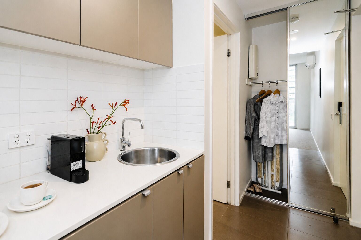 Eine moderne Küche mit Spüle, Kaffeemaschine und einer Vase mit Blumen.