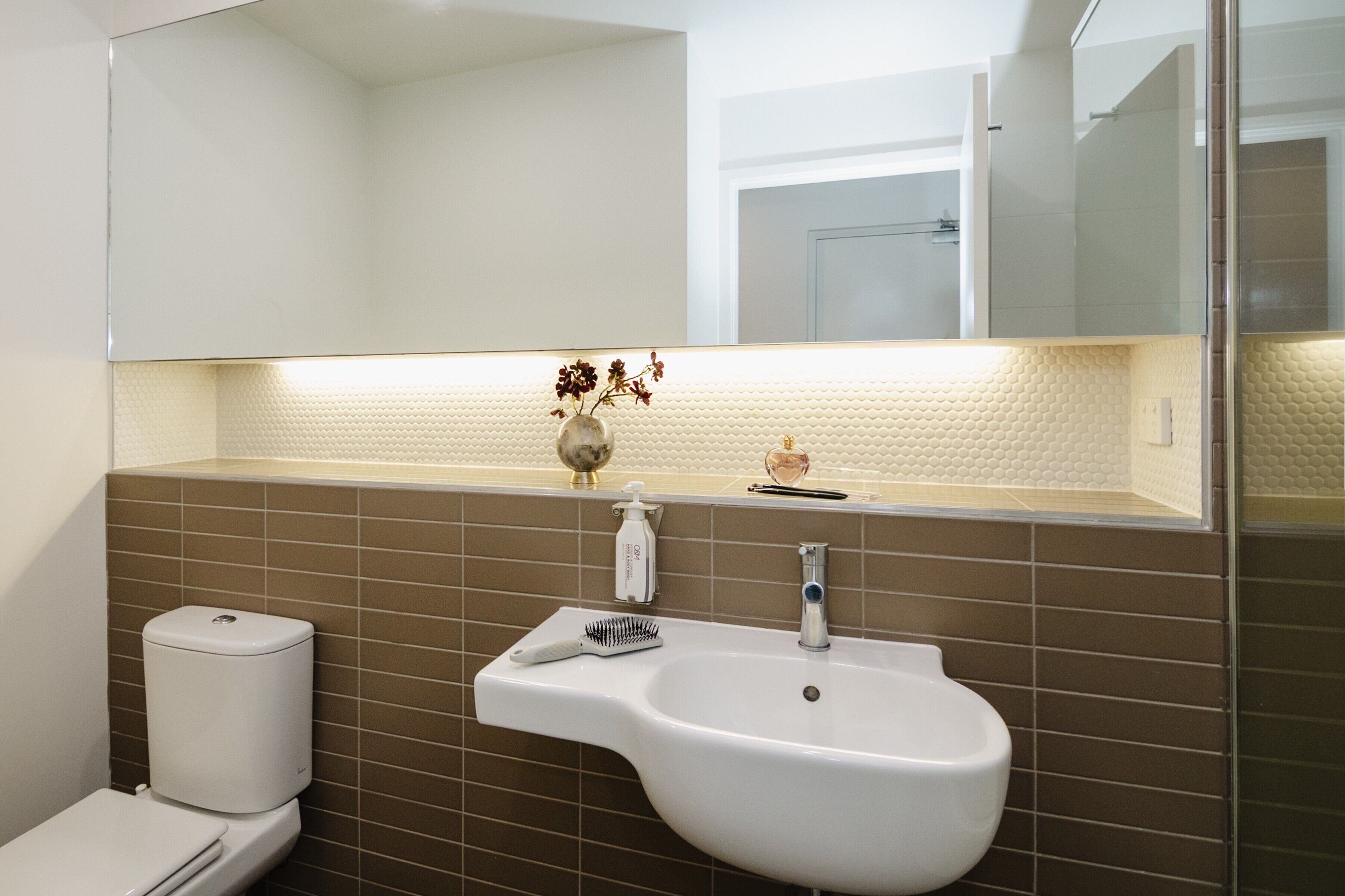 A bathroom with a white sink, a mirror above it, and a toilet to the left.