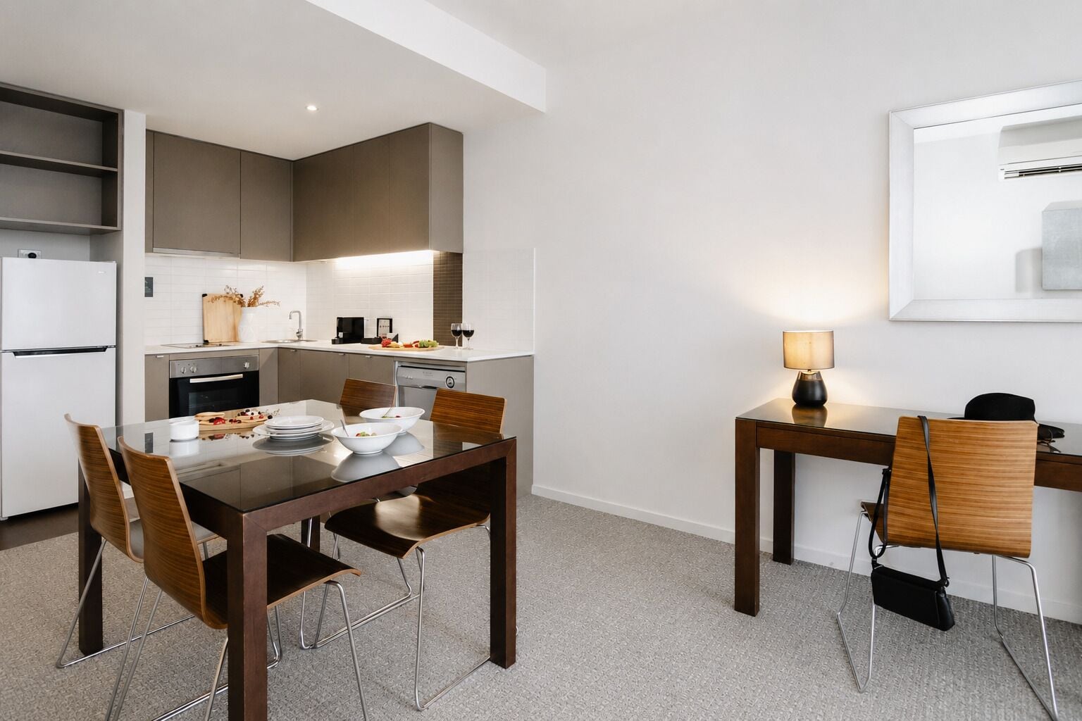 Una cocina moderna con zona de comedor, que incluye una mesa con sillas, un refrigerador y una cafetera.