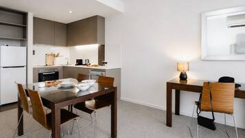 Una cocina moderna con zona de comedor, que incluye una mesa con sillas, un refrigerador y una cafetera.