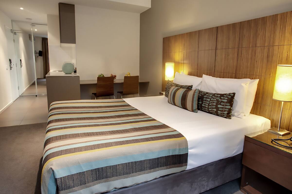Una habitación de hotel con una cama grande, un escritorio, una silla y una lámpara.