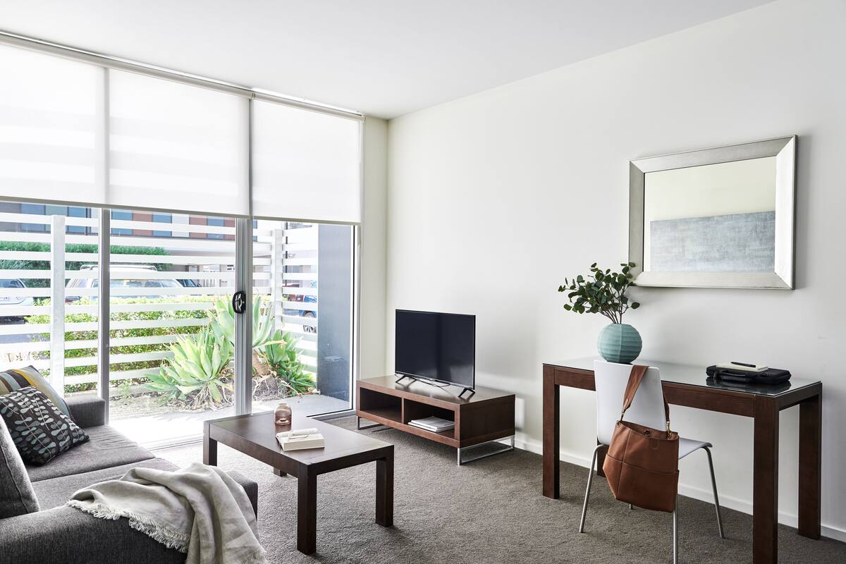 Una sala de estar moderna con un sofá, una mesa de centro, un mueble para televisión y una silla.