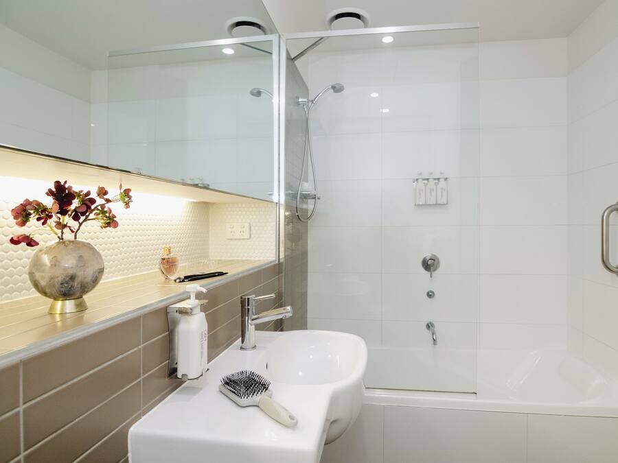 A modern bathroom with a glass shower enclosure, a white sink, and a vanity with a mirror.