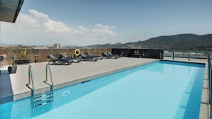 A rooftop swimming pool with sun loungers and a view of distant mountains. - Hotel Sercotel Ciutat de Montcada (Montcada I Reixac)