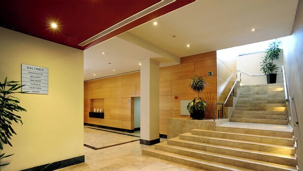 A hotel lobby with a marble floor, a staircase, and a sign listing room types. - Hotel Sercotel Ciutat de Montcada (Montcada I Reixac)