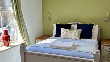 Un dormitorio con cama, una ventana con cortinas, un jarrón rojo y un respiradero en el techo.