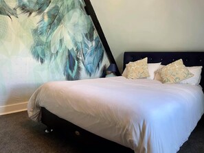 A bed with white bedding, a dark headboard, and patterned pillows.