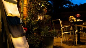 An outdoor seating area with a brick wall, potted plants, and a table with chairs. - The Mansion House Hotel (Spalding)