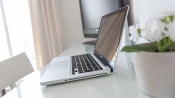 Un ordinateur portable est posé sur un bureau, avec une plante en pot à côté.