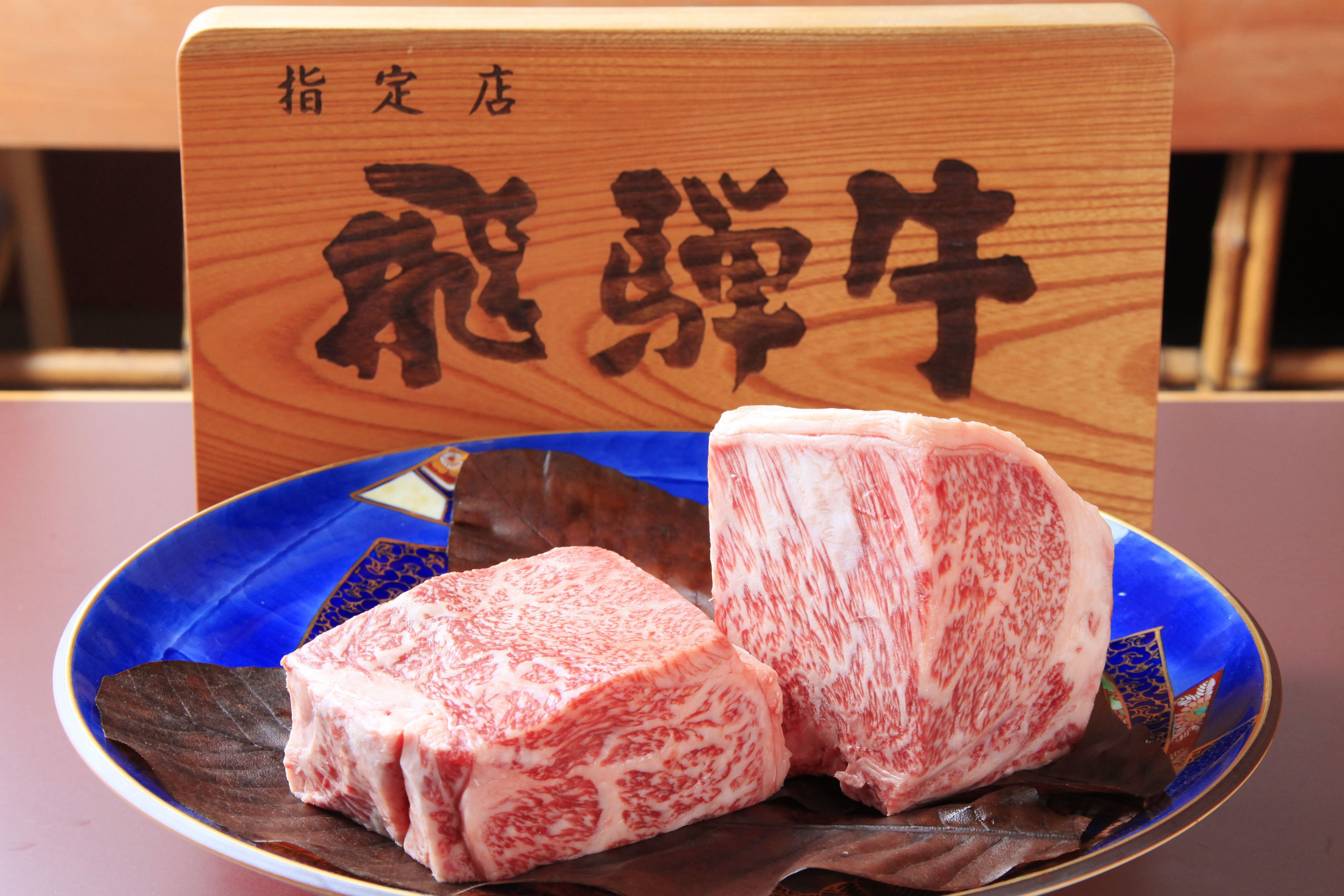 A plate with two pieces of meat and a wooden sign with Japanese characters.