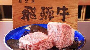 A plate with two pieces of meat and a wooden sign with Japanese characters.