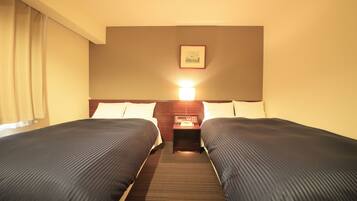 Una habitación de hotel con dos camas, una mesita de noche con una lámpara y un cuadro en la pared.