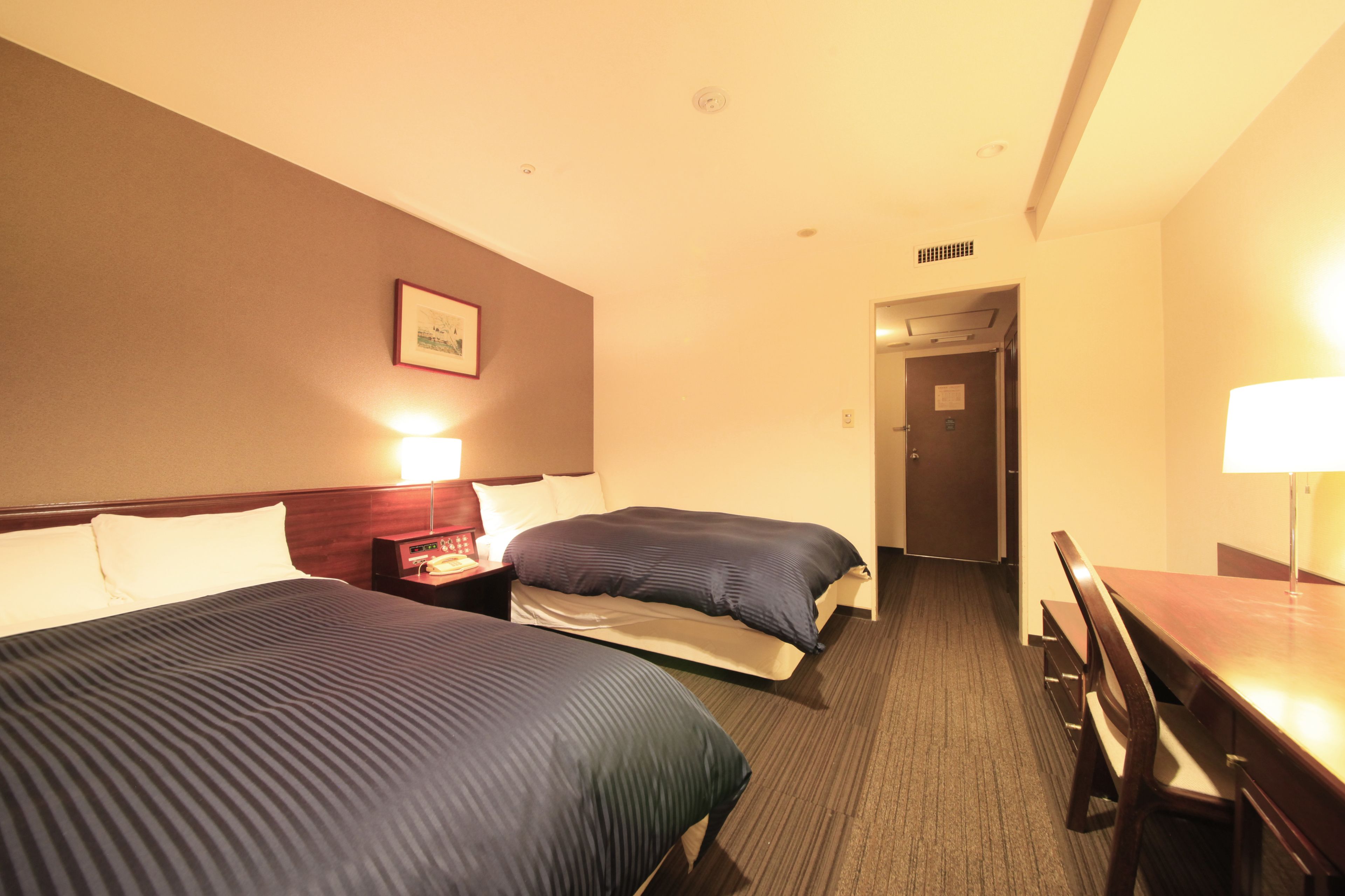 Ein Hotelzimmer mit zwei Betten, einem Schreibtisch und einem Stuhl.
