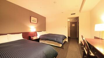 Ein Hotelzimmer mit zwei Betten, einem Schreibtisch und einem Stuhl.