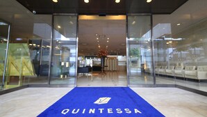 A hotel entrance with a blue carpet and the name 'QUINTESSA' on it.