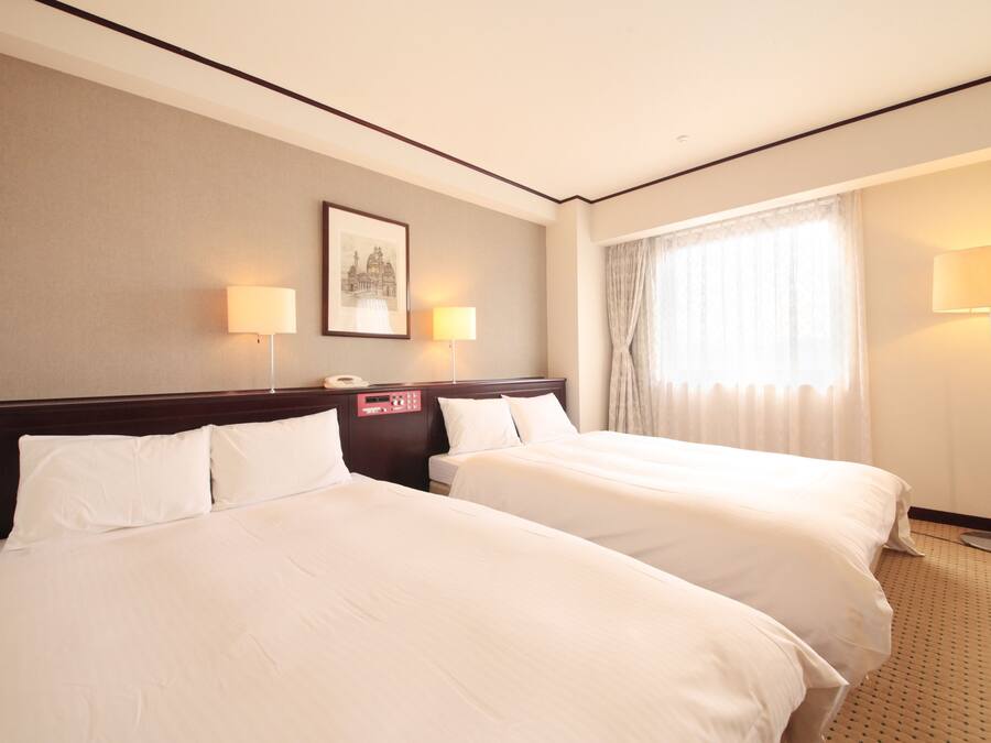 A hotel room with two beds, a nightstand with a phone, a framed picture on the wall, and a window with curtains.