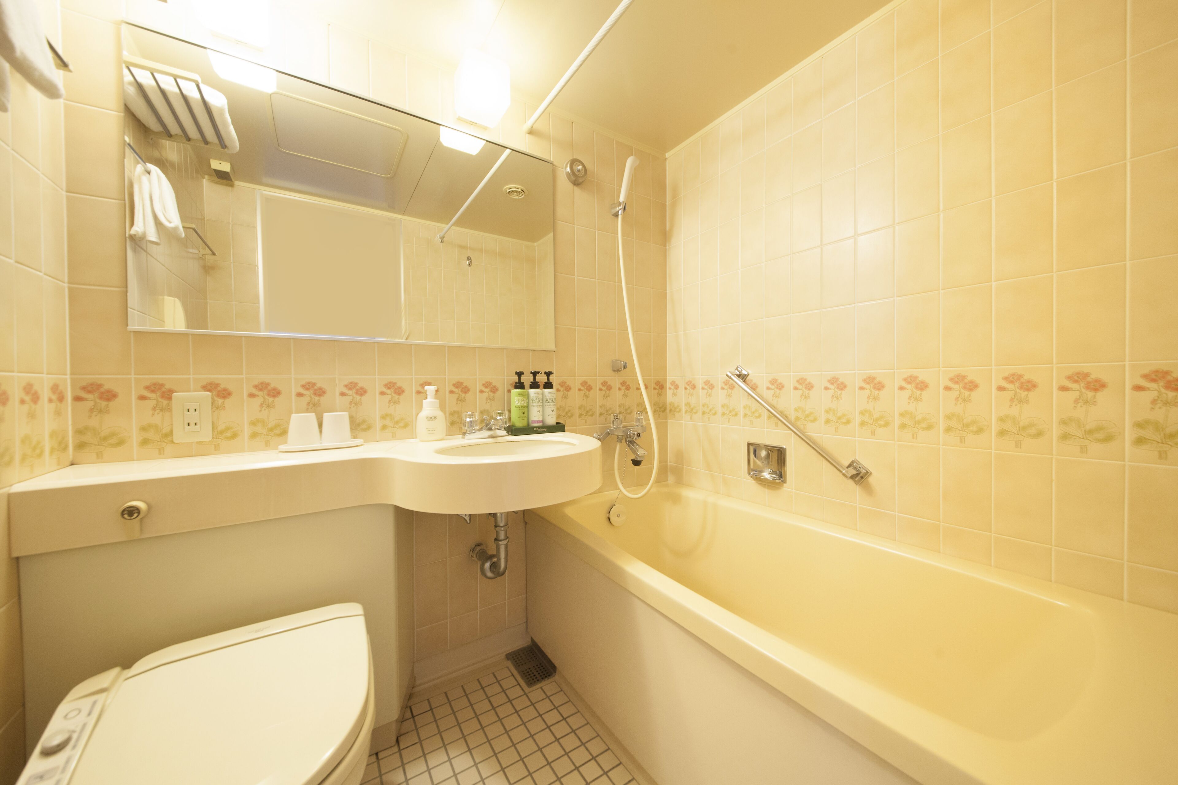 Un baño con lavamanos, espejo, inodoro y bañera.