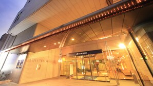 A hotel entrance with a modern design, featuring a glass facade and a sign that reads "QUINTESSA".