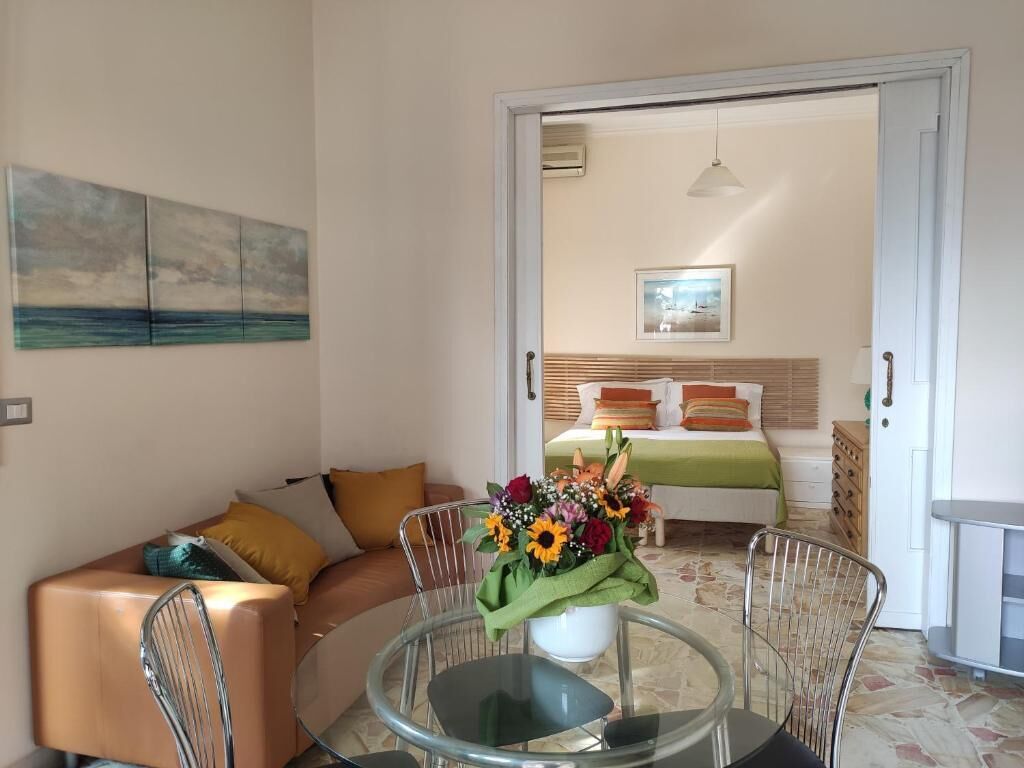 Una sala de estar con una mesa de vidrio, un sofá y un cuadro en la pared.