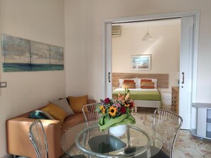 Una sala de estar con una mesa de vidrio, un sofá y un cuadro en la pared.