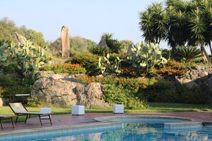 Una piscina al aire libre, sillones reclinables de piscina