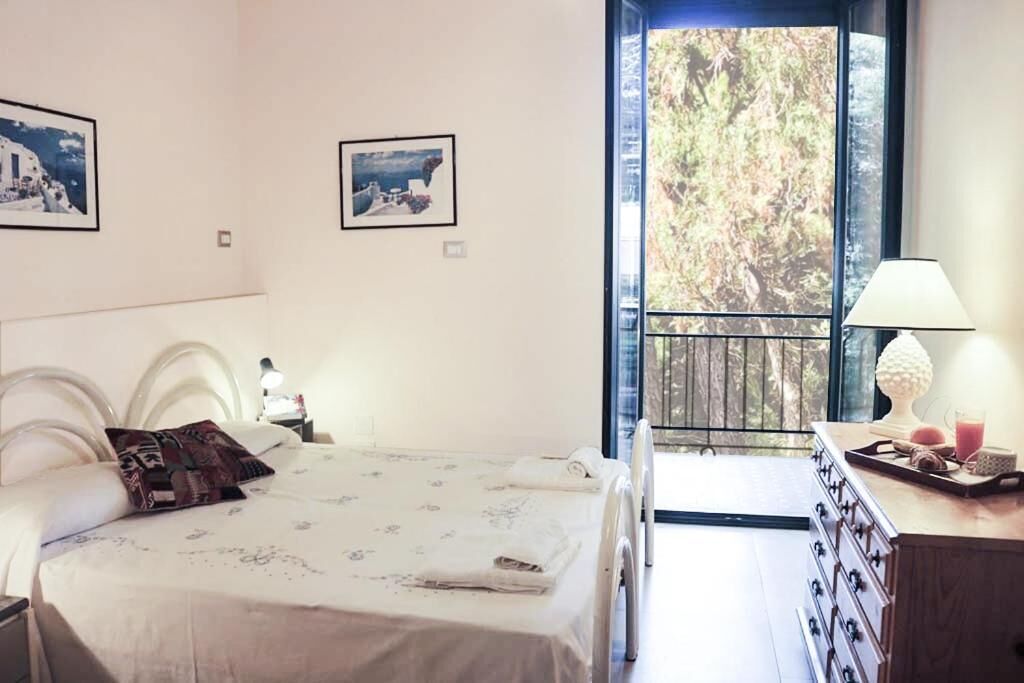 A bedroom with a bed, a dresser, a nightstand, and a window with a view of trees.