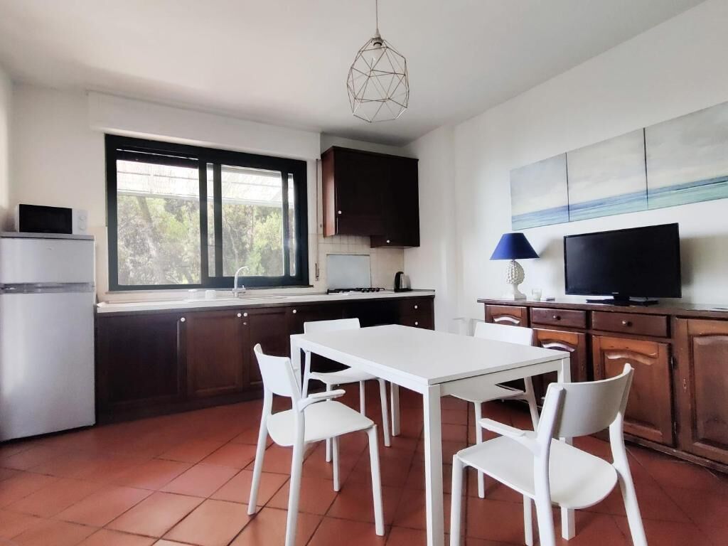 Una cocina con una mesa de comedor, sillas, un televisor y armarios.