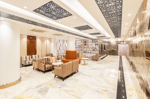 A spacious lobby with a marble floor, striped sofas, and a central seating area.