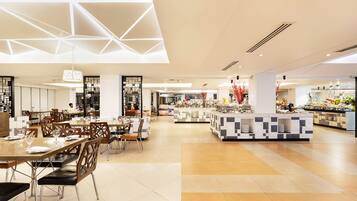 A modern dining area with geometric ceiling design, a central buffet, and a variety of seating arrangements.