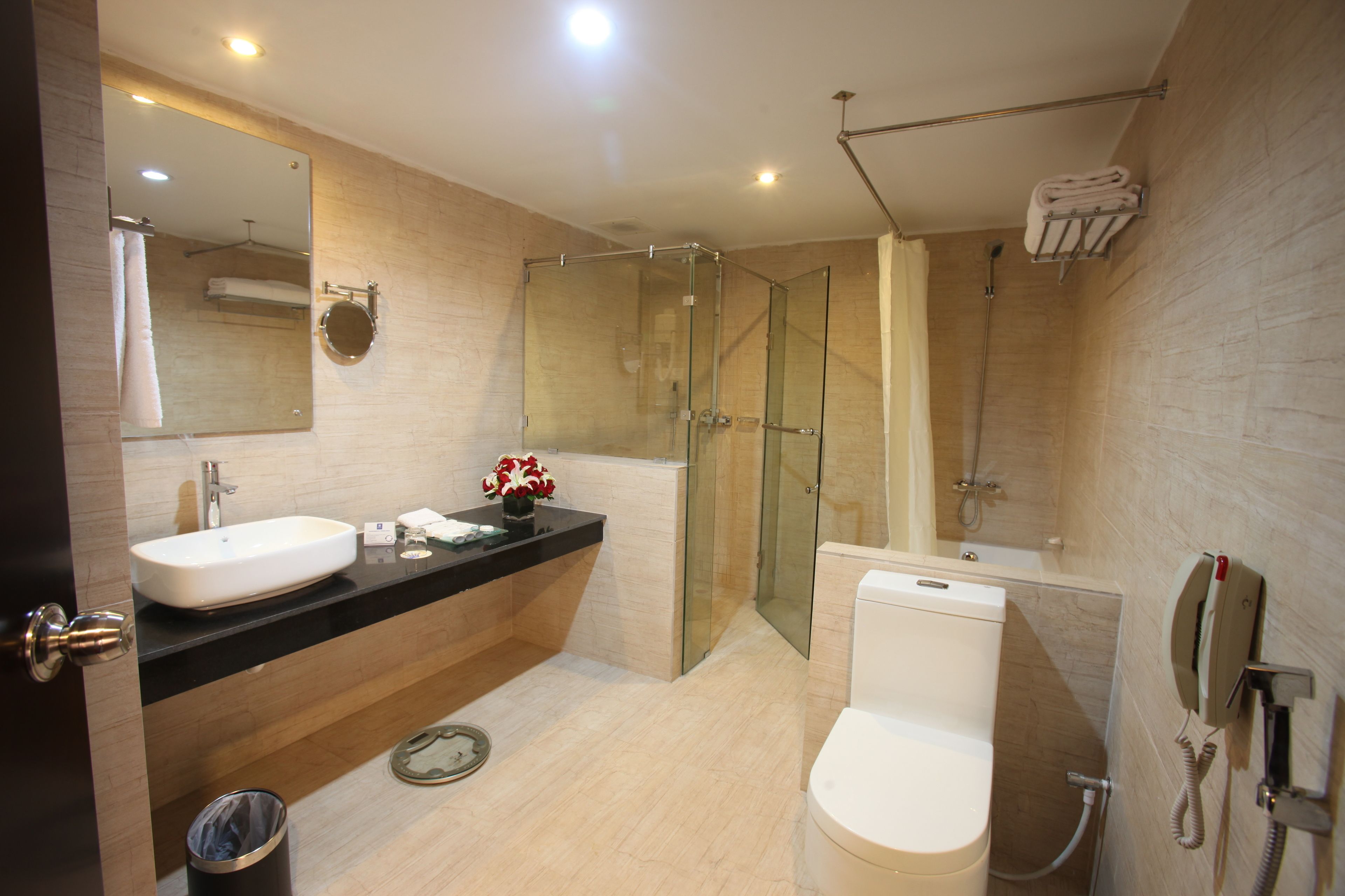 A modern bathroom with a large mirror, two sinks, a toilet, and a shower area.