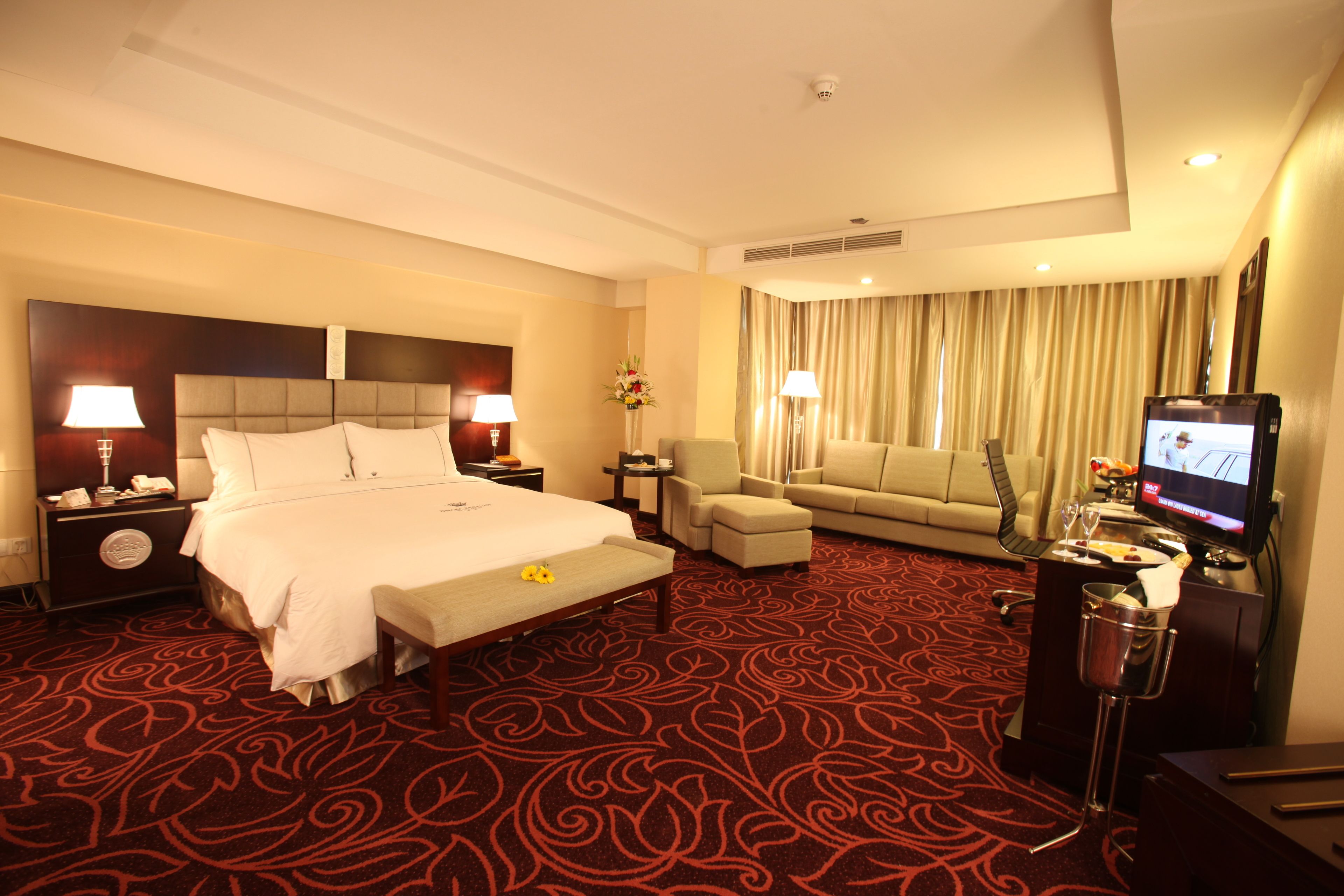 Een hotelkamer met een groot bed, een slaapbank, een televisie en een minibar.