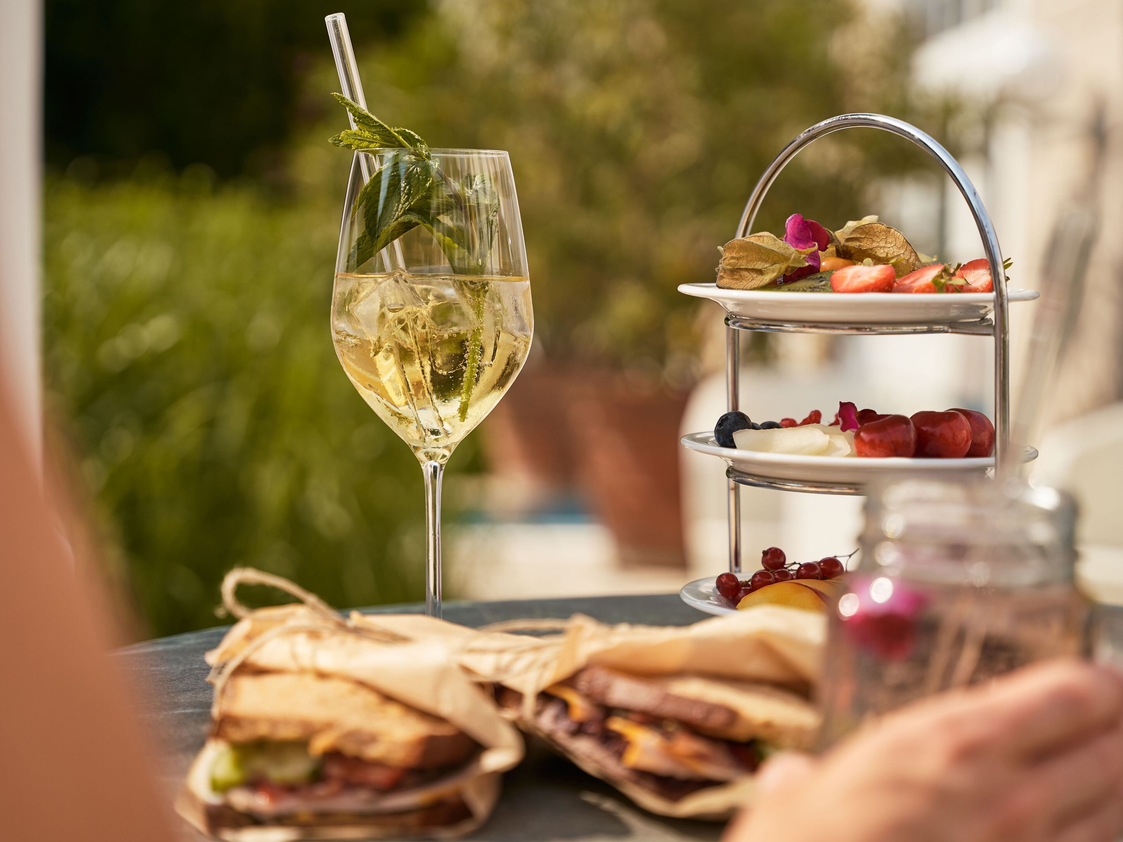 Ein Tisch mit einem Weinglas, einer Obstplatte und Sandwiches.