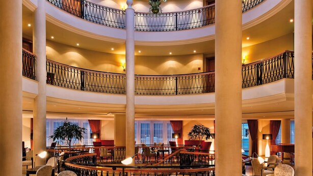 A multi-level atrium with a central chandelier, tiered balconies, and seating areas.