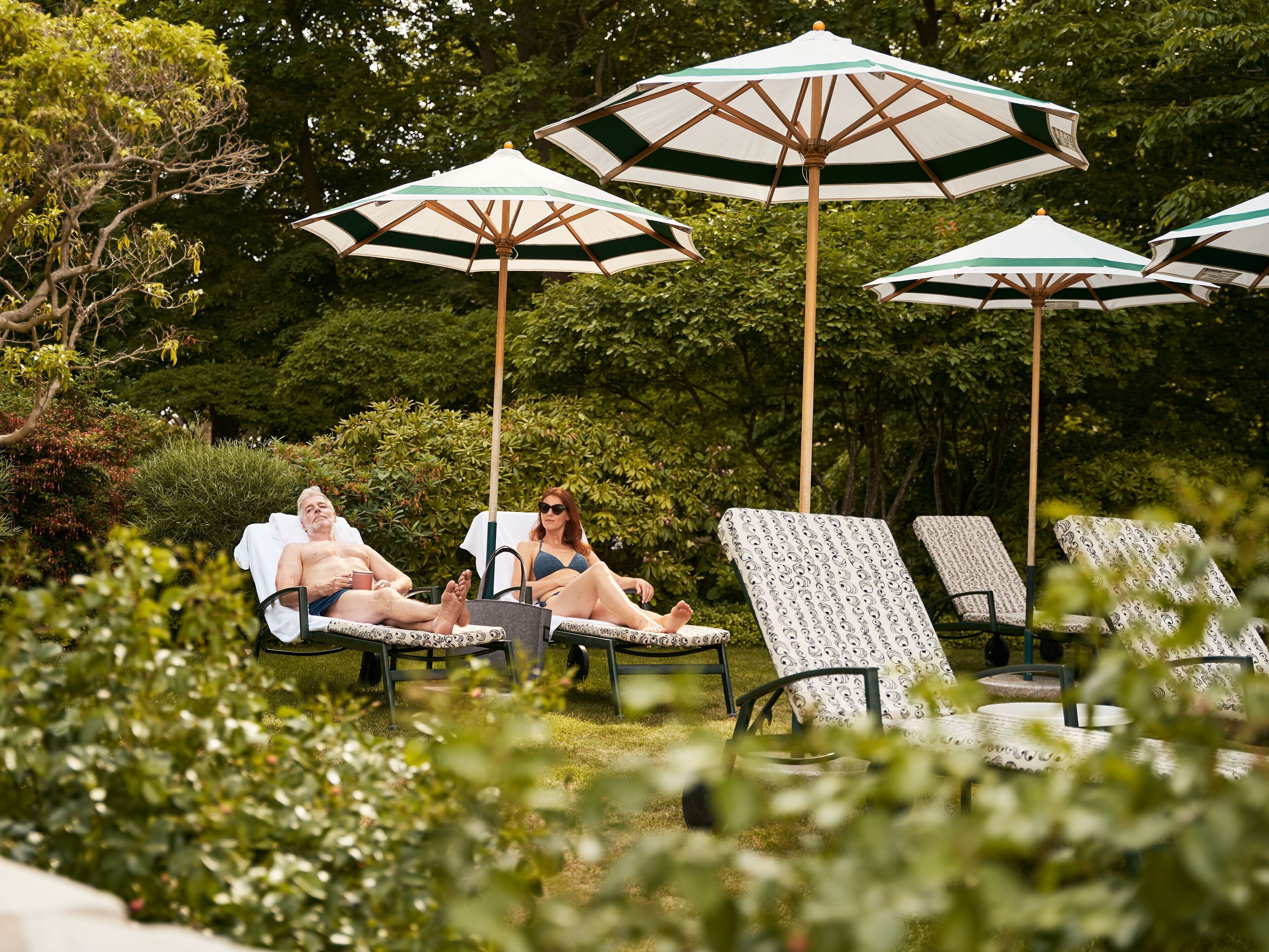 Un jardín con sillones de descanso y sombrillas.