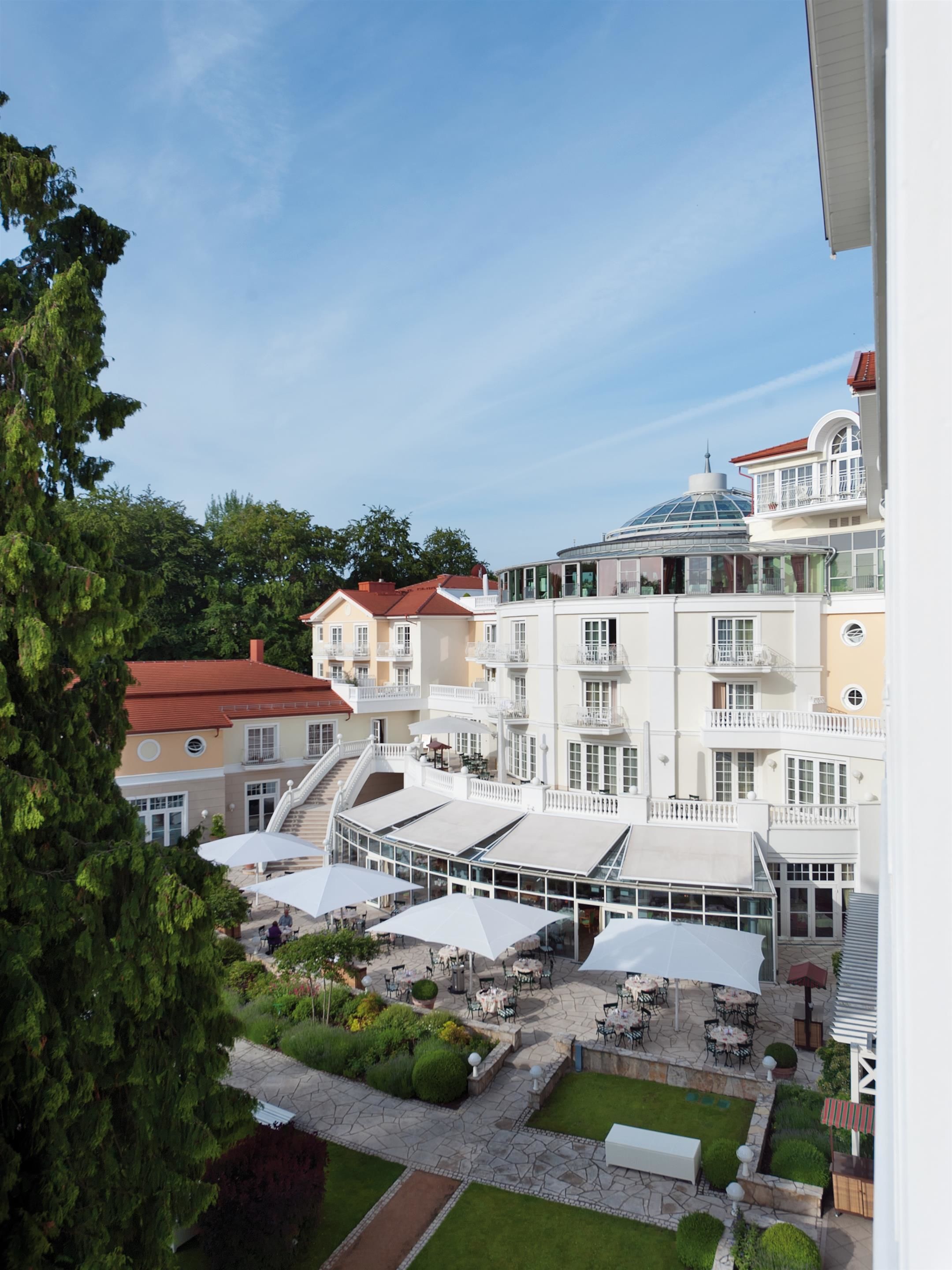A hotel with multiple balconies, outdoor seating areas, and a well-maintained garden.