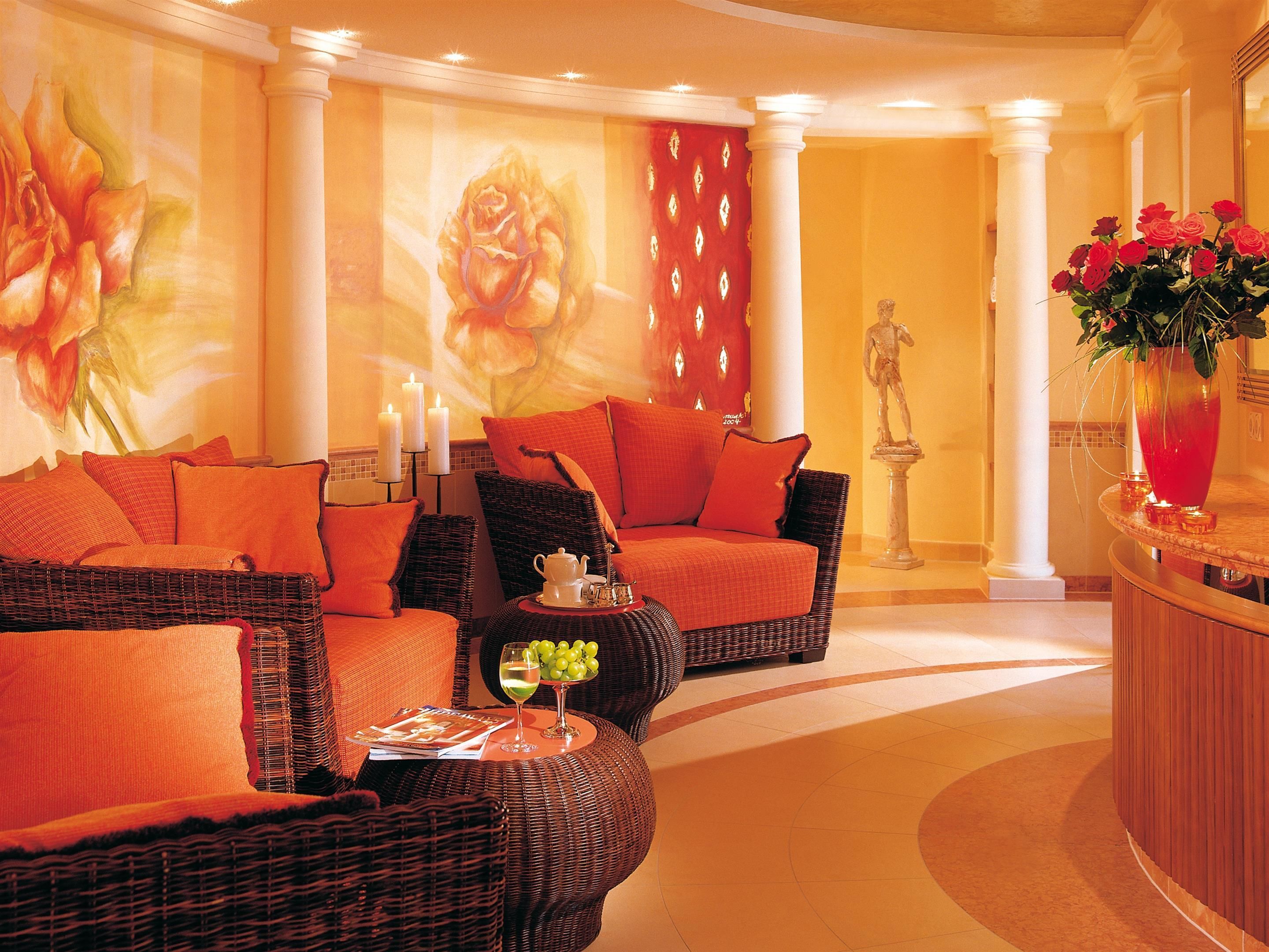A luxurious lobby with wicker furniture, a large floral mural, and a statue.