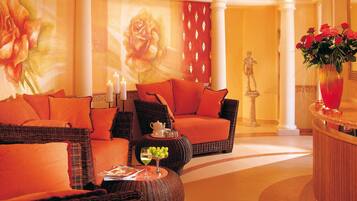 A luxurious lobby with wicker furniture, a large floral mural, and a statue.